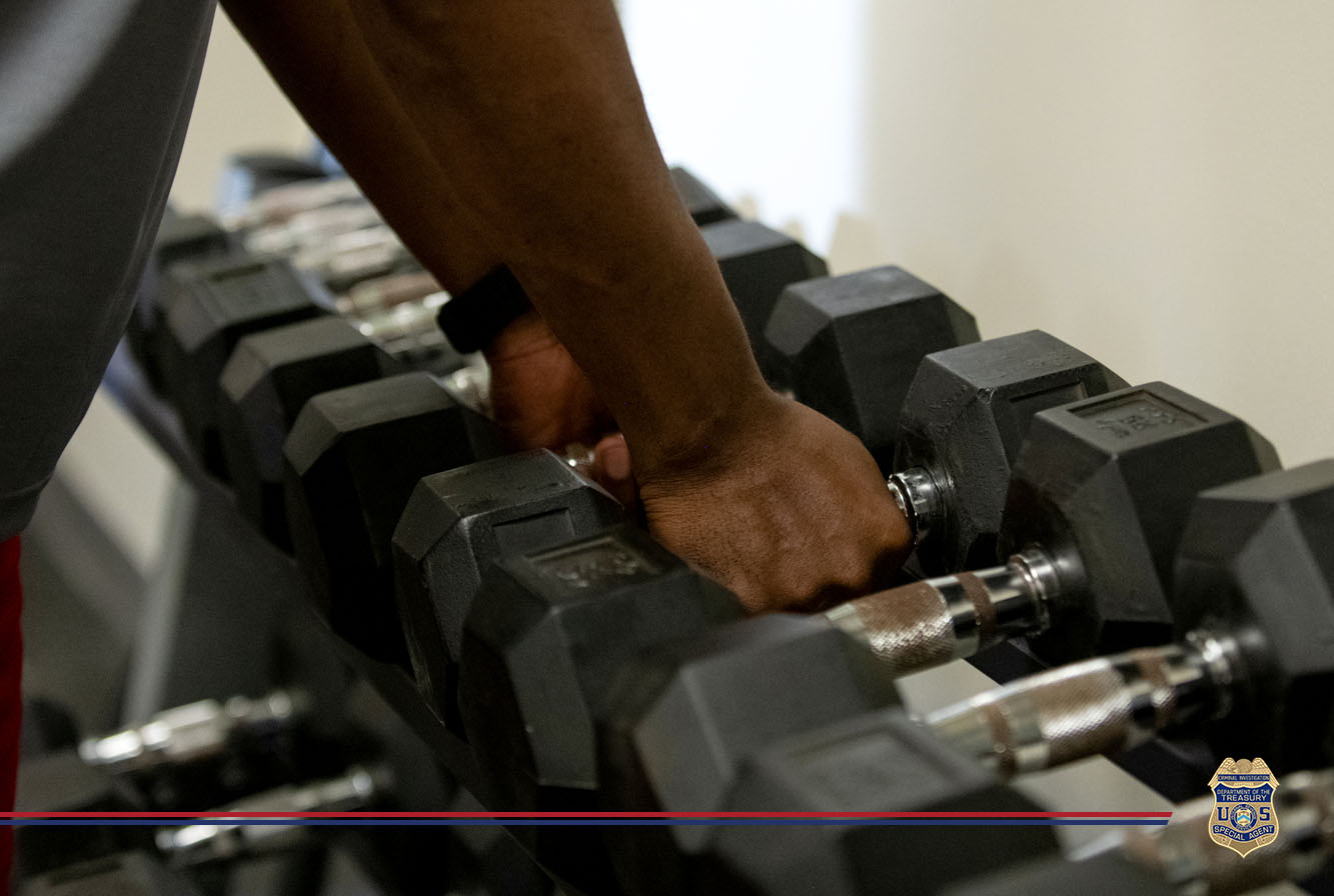 A person selecting a dumbbell from a rack in a gym, focusing on their hand gripping the weight.