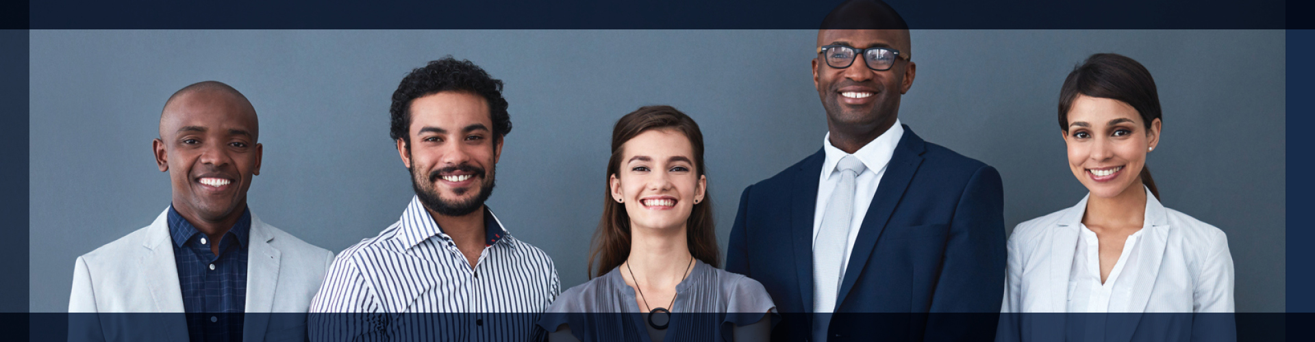 Group portrait of five professionals, each displaying a confident smile, dressed in smart business attire against a gray backdrop. The image reflects a dynamic and collaborative team, showcasing unity and professionalism in the workplace