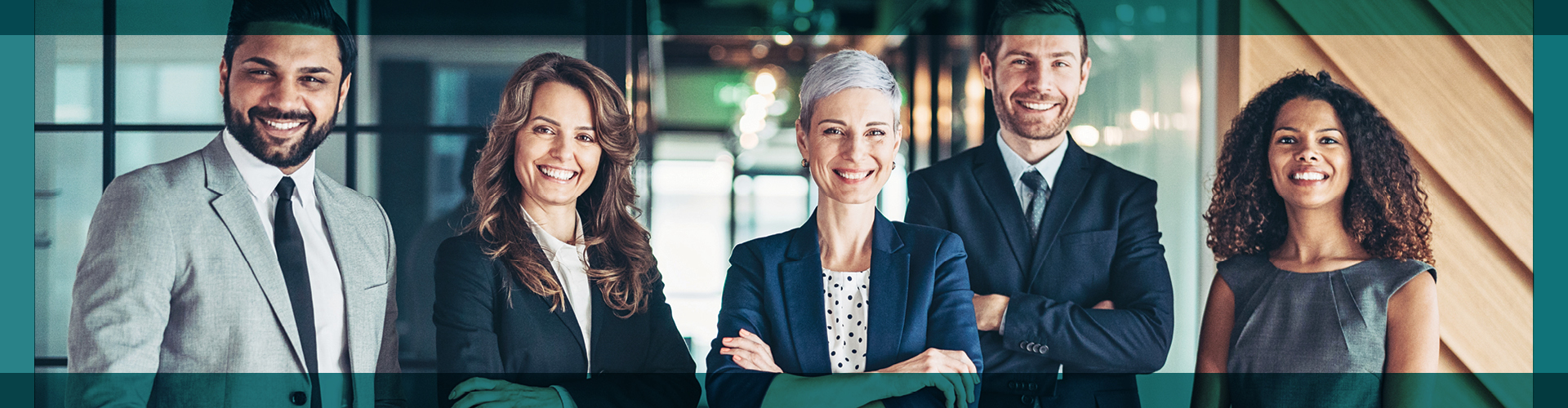 Confident group of five professionals standing in a modern office environment, each with a friendly smile. They are dressed in business attire, presenting a strong, united team ready to tackle their next business challenge.